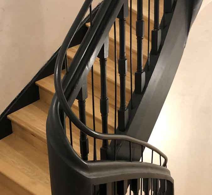 Wendeltreppe in hellem Holz mit einem schwarzen Treppengeländer ebenfalls aus Holz
