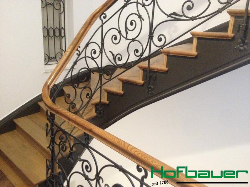 Treppengeländer im Jugendstil: Verschnörkelte Details aus schwarzem Metall in Kombination mit hellem Holz