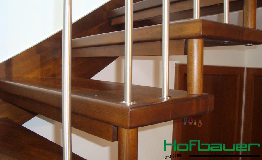 Handlauftragende Treppe in dunklem Holz und einem Treppengeländer aus Holz und Metallstäben in der Nahaufnahme