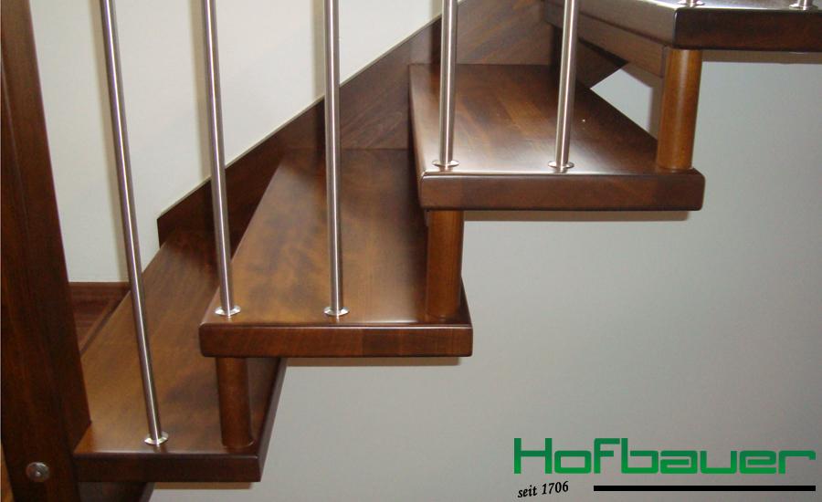 Handlauftragende Treppe in dunklem Holz und einem Treppengeländer aus Holz und Metallstäben von der Seite
