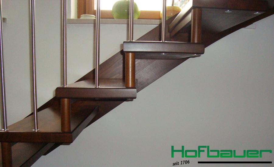Handlauftragende Treppe in dunklem Holz und einem Treppengeländer aus Holz und Metallstäben von der Seite