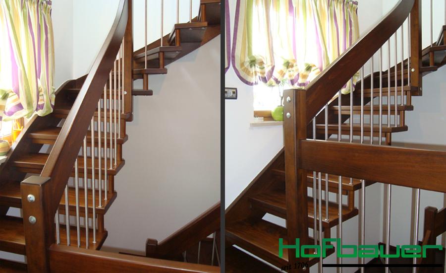 Handlauftragende Treppe in dunklem Holz und einem Treppengeländer aus Holz und Metallstäben